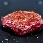 A cell-cultured beef burger patty being fried.
