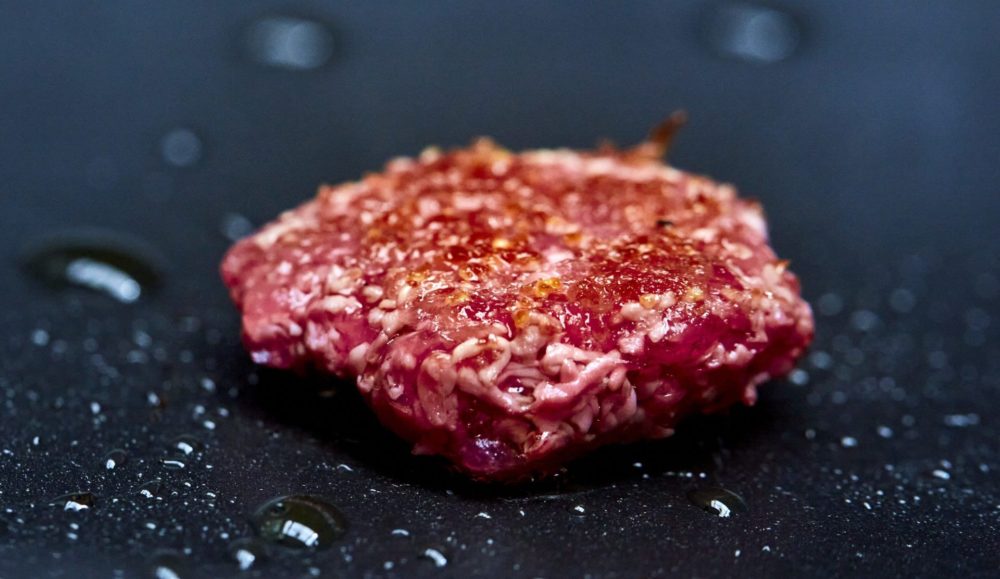 A cell-cultured beef burger patty being fried.