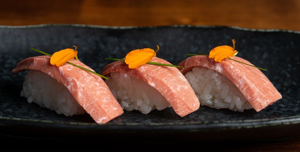 BlueNalu's bluefin tuna toro nigiri, topped with sliced chives and nasturtium petals